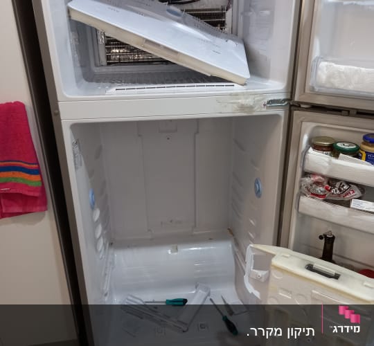 מקרר פתוח עם כלים לתיקון וחלקים מפורקים